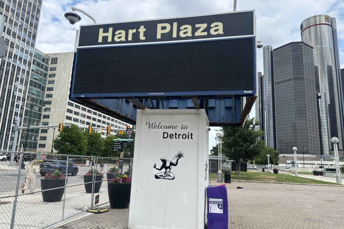 Hart Plaza sign with downtown Detroit towers and the Renaissance Center behind it